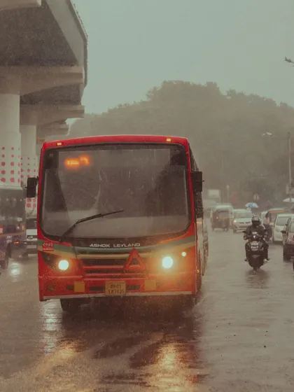 A BEST bus navigating the rainy streets of Powai. The glowing headlights in the downpour create a very cinematic and moody atmosphere.