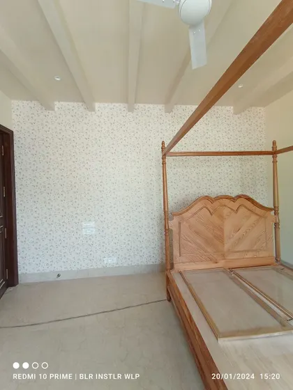 A light, subtle patterned wallpaper in a bedroom with a four-poster bed.