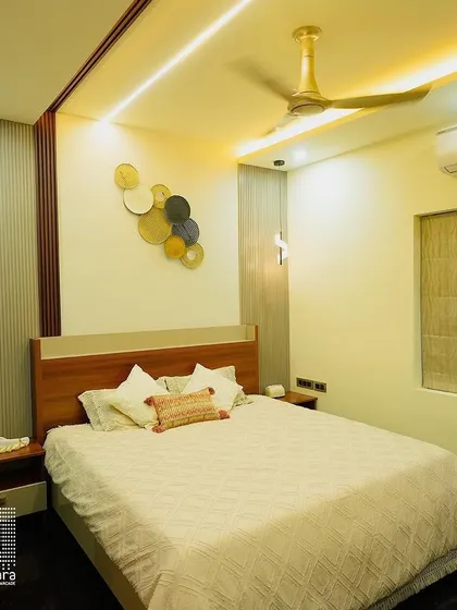 A warm and inviting bedroom design with a custom wooden headboard and integrated side tables. The circular metal wall art and unique bedside lamp add a touch of modern artistry.