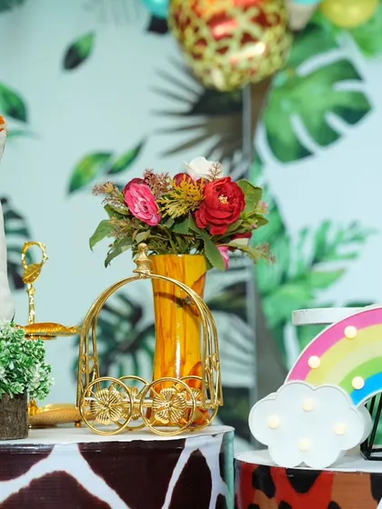 A close-up of the decor details from a jungle-themed party, including a giraffe plushie, floral arrangements, and a light-up rainbow prop.
