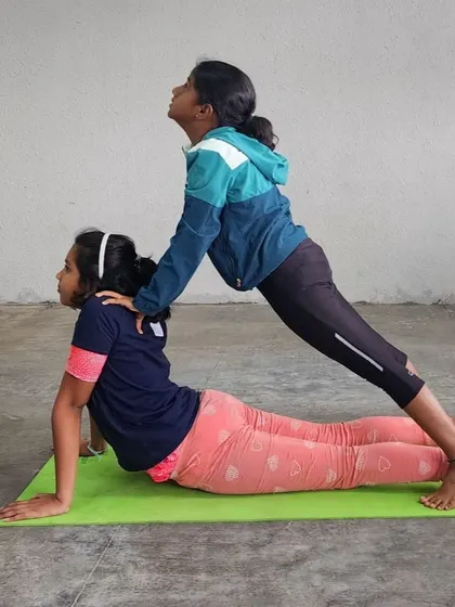 Two girls demonstrate a perfect partner-assisted backbend, working together to improve their flexibility.
