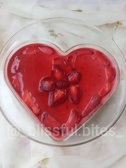 A top-down view of my heart-shaped Strawberry Cheesecake, showing the glossy strawberry topping and fresh fruit decoration.