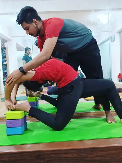 Blocks and hands-on adjustments are used here to help a student safely work on their Ustrasana (Camel Pose), protecting the lower back while opening the chest.