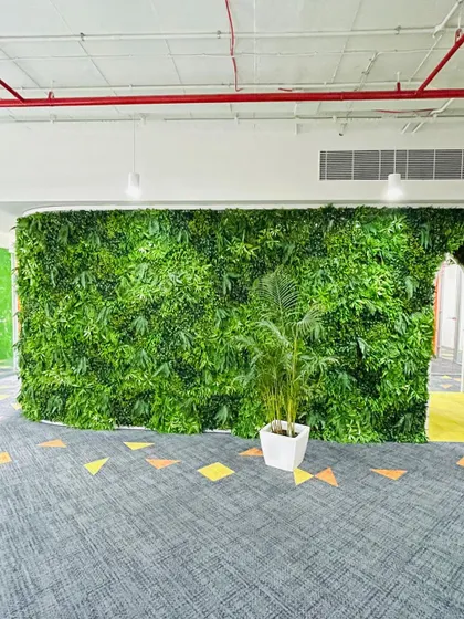 A large artificial green wall installed in a corporate office, providing a beautiful natural backdrop for the workspace.