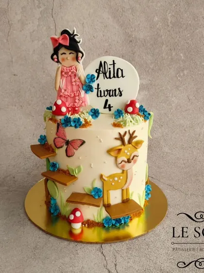 A mystical garden theme for Alita's 4th birthday. This 1 kg cake features a custom Coffee Ferrero Crunch flavor and is decorated with a sweet girl figurine, a deer, mushrooms, and butterflies.