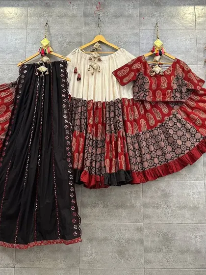 A playful and stylish red, black, and white chaniya choli. The tiered skirt and printed blouse create a fun and modern silhouette.