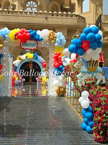 A wide-angle view of the grand entrance for a carnival party, showing multiple balloon arches and a carousel horse prop.