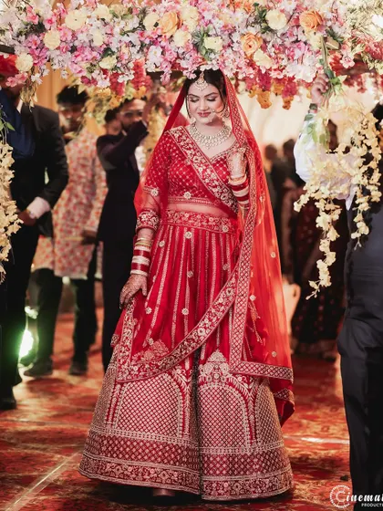 The bride makes her entrance under a beautiful floral archway, a classic and elegant moment on her wedding day.