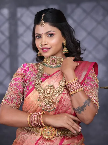 The beauty of temple jewellery is in its details. This bride is wearing a full set featuring a prominent Lakshmi pendant on the long necklace, a matching choker, and jhumkas.