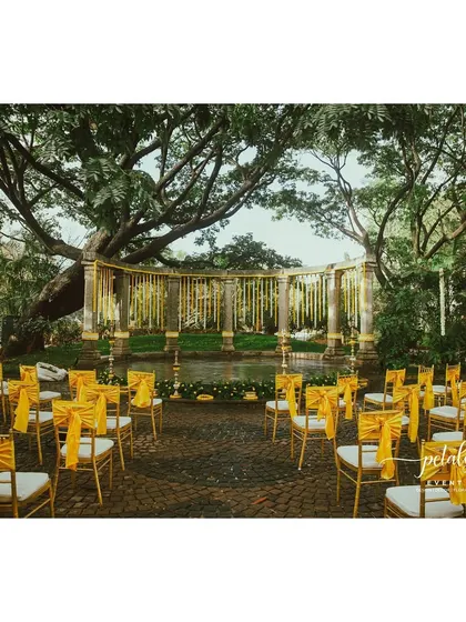 A stunning view of the Indradhanush event space at Shankaraa Foundation, where I created a minimalist yet traditional setup. The stone pillars are adorned with simple marigold and chrysanthemum streamers, perfectly complementing the natural beauty of the venue.