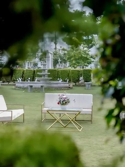 A quiet seating nook in a garden setting, perfect for guests to relax and mingle during an outdoor wedding celebration.