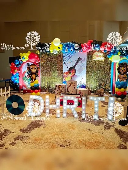 A lively music-themed stage for a first birthday, featuring a grass-like backdrop, musical note props, and character cutouts playing instruments.