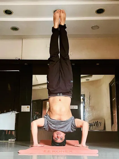 A clear, straight-on view of a tripod headstand, showcasing core strength and stability. This is a foundational inversion we work on in my advanced yoga classes.