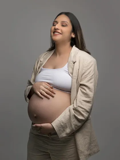 A candid, happy moment during the maternity shoot. Her subtle makeup look appears fresh and effortless, perfect for capturing these precious memories.