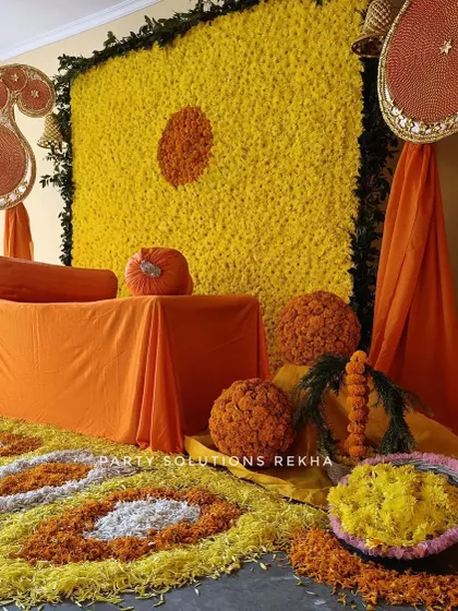 A classic Haldi setup focused on the beauty of marigolds. The wall of yellow flowers, paisley motifs, and a floor covered in petals creates a traditional and auspicious setting for the ceremony.