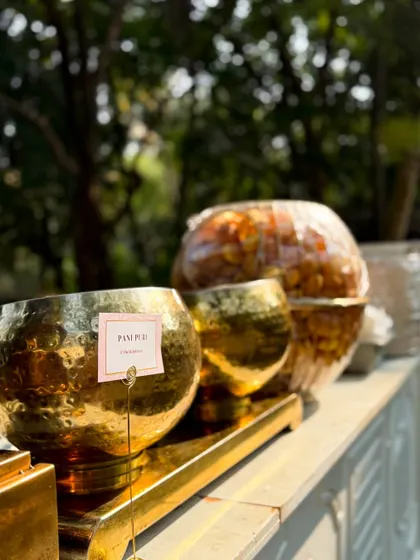 The Pani Puri station is ready for service at an outdoor event. The golden bowls and fresh ingredients promise a delightful and authentic chaat experience.