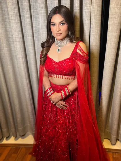 This full-length shot shows how the flowing waves balance the structure of the embellished red lehenga, creating a stunning bridal look.