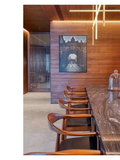 The dining area of the Bombay Penthouse, featuring a bespoke Abu Black marble table and custom lighting. The space is lined with salvaged teak, creating a warm and inviting atmosphere for entertaining.