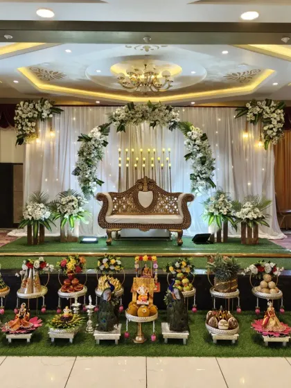 An elegant and modern take on traditional decor for a Half-Saree program. This setup features a full arch of white gerberas and fresh greenery against a clean white drape, with candle-like lighting adding a touch of sophistication.