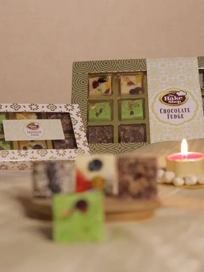 Our Chocolate Fudge is available in beautifully designed gift boxes. The packaging features a window to showcase the colorful and decadent fudge squares inside.