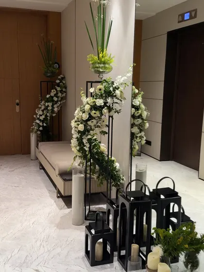 We use decor to enhance architectural features. Here, a cascading floral arrangement on a modern stand and a collection of black lanterns beautifully accent an entryway near an elevator.