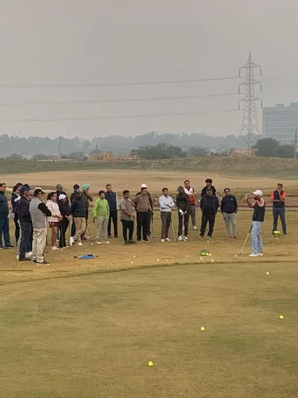 A wide shot of the Short Game Masterclass, showing the group spread out on the practice green as they learn new techniques.