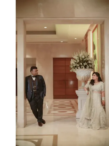 A classic, elegant portrait of Gagan and Shalini in a grand hotel corridor. The formal composition and their sophisticated attire create a timeless and stately image.