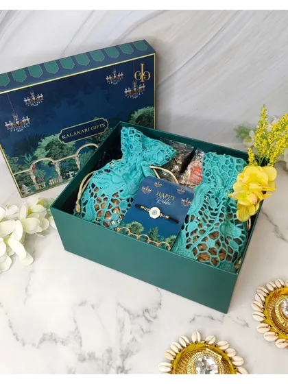 A traditional yet modern Rakhi hamper in a deep green box. It contains beautiful lace potli bags filled with treats and a simple, elegant rakhi.