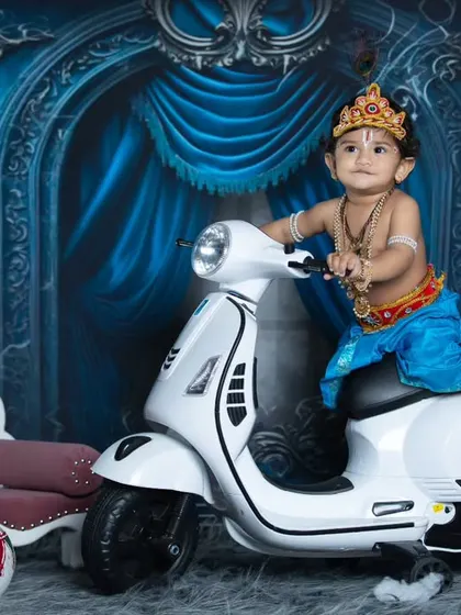 A classic pose of little Krishna on his scooter, looking ready for some mischief.