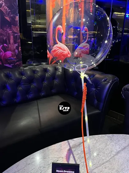A simple yet effective decor piece: a clear bubble balloon with LED lights, reflecting the neon flamingos in the background.