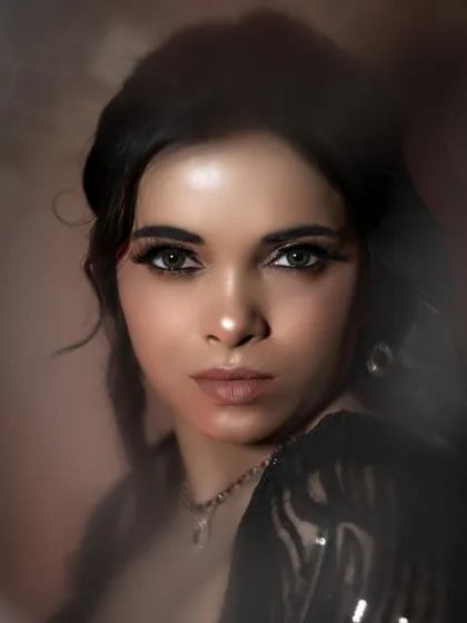 A close-up portrait from the black dress series, where soft, diffused light beautifully illuminates the model's face. This shot focuses on the stunning makeup and the emotion in her eyes.