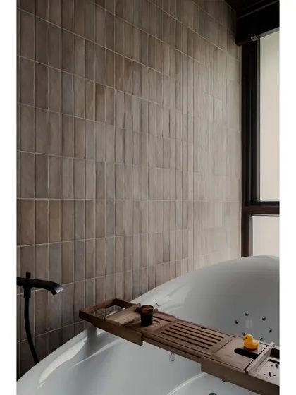 A close-up of the bathtub, a perfect spot for a relaxing soak. The wooden bath tray adds a natural, spa-like element.
