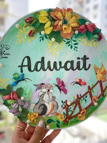 A whimsical nameplate for a child's room, featuring the name "Adwait" alongside a cute sculpted bunny, butterflies, and a fence. The soft green base and warm-toned flowers create a cheerful and playful scene.