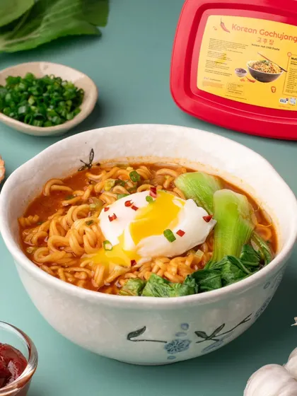 Another angle of the delicious Gochujang ramen, this time capturing the moment the poached egg yolk breaks. This action adds a dynamic and mouth-watering element to the photograph.