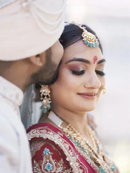 A close-up of the bride's makeup, showing the delicate bindi, winged eyeliner, and soft shimmer on the eyelids that make her eyes sparkle.