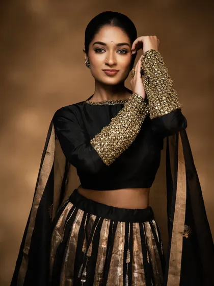 A modern and chic look featuring a black and gold lehenga. The makeup is soft glam, with a focus on glowing skin and defined eyes.