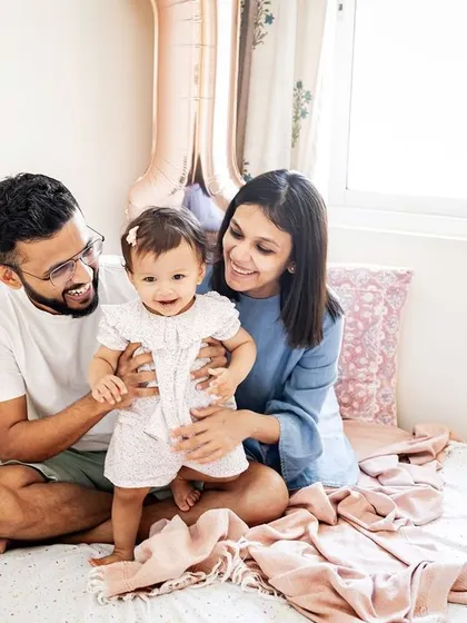 A happy family moment on the bed, celebrating their daughter's first birthday. These candid, at-home sessions are all about capturing genuine smiles and interactions.