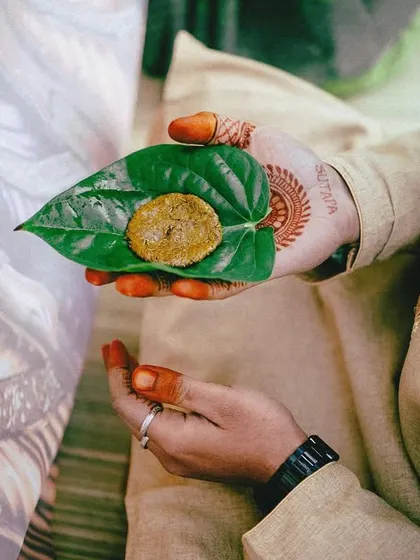 A detail shot of the groom's hand holding a paan leaf with jaggery, part of a traditional Telugu wedding ceremony. These small details are rich with cultural significance.