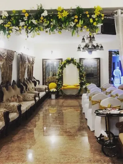 An indoor Haldi ceremony setup with an elegant floral arch and seating for guests. The overhead floral runner adds a touch of luxury to the intimate space.