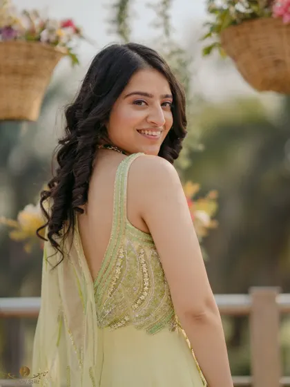 A beautiful back-shot of the bride-to-be, showing off the delicate embroidery on her pastel green outfit and her lovely curls.