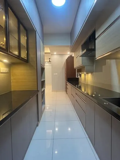 A view down a galley kitchen with extensive storage on both sides. The glass-fronted upper cabinets and under-cabinet lighting make the narrow space feel more open and bright.