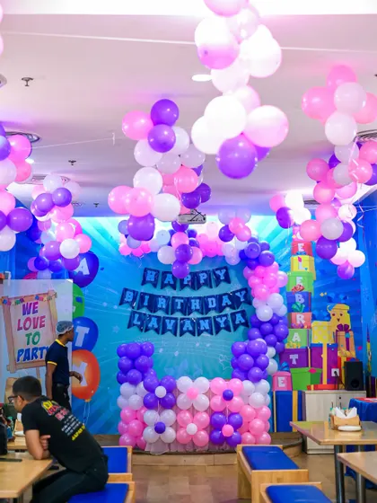 A full view of a party room decorated in pink and purple. Our team transforms the space with elaborate balloon displays hanging from the ceiling and around the cake table.