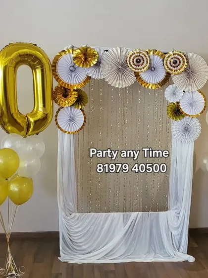 A simple yet elegant 50th birthday photo corner with a shimmer backdrop, paper fans, and a large number '50' foil balloon.
