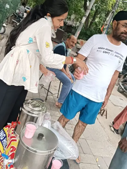 Serving the community includes people from all walks of life. Here, a volunteer offers a cool drink to a gentleman, embodying the spirit of respect and care that defines *Sachi Sewa*.