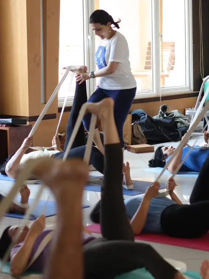 A class of students using belts for leg stretches. This is a fundamental practice that we return to again and again to build a strong foundation.