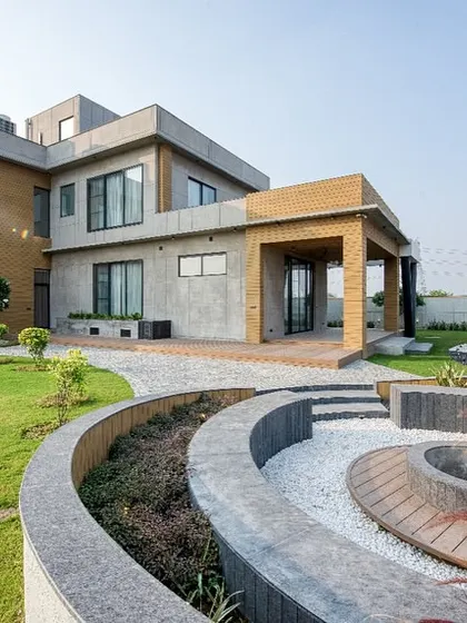 For this modern farmhouse in Sonipat, the design integrates the structure with its natural surroundings. I used a mix of textured concrete and warm brick, complemented by a sunken fire pit and curved landscaping to create a seamless indoor-outdoor living experience.