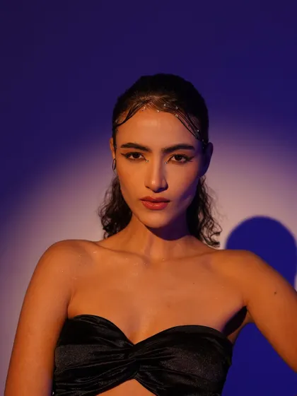 A beauty-focused portrait using a combination of warm and cool lighting. The purple background and the warm key light on the model's face create a beautiful color contrast.