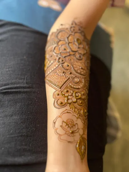 A close-up of the detailed floral and paisley work on the forearm.