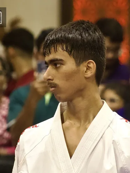 The focused profile of a competitor, sweat on his brow, looking on during a tournament. This is the look of a student analyzing the fight and preparing for his turn.