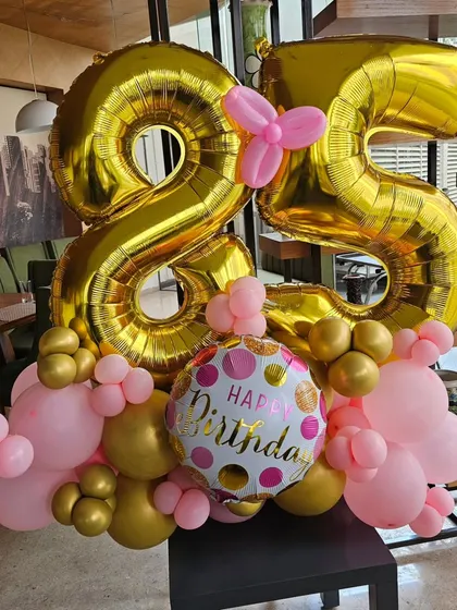 A chic and cheerful balloon arrangement for a 25th birthday. The large gold foil numbers are paired with pink and gold balloons for a fun and celebratory centerpiece.